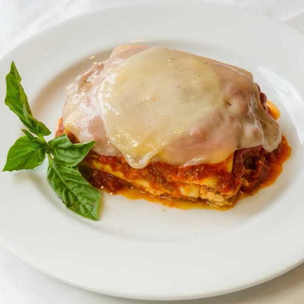 A serving of Armettas Italian Grill and Pizzeria's lasagna, topped with melted cheese and fresh basil.